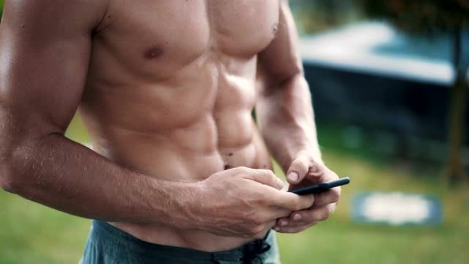 近距离看，赤裸上身的肌肉男正在用手机发信息