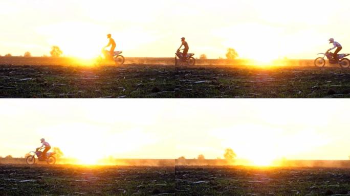 骑摩托车的人站在摩托车上穿越日落。朋友们在黄昏时积极休息户外驾驶强大的摩托车。骑自行车的人喜欢旅行。
