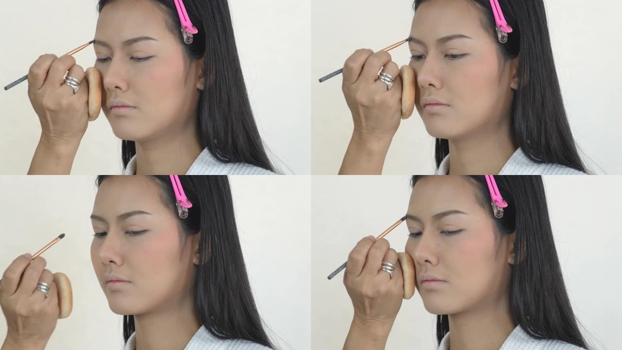 化妆师向白底美女展示右眉区域化妆的过程