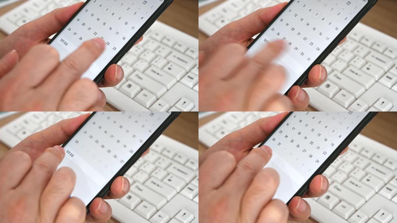 使用智能手机日历应用程序的男人的手的特写镜头。