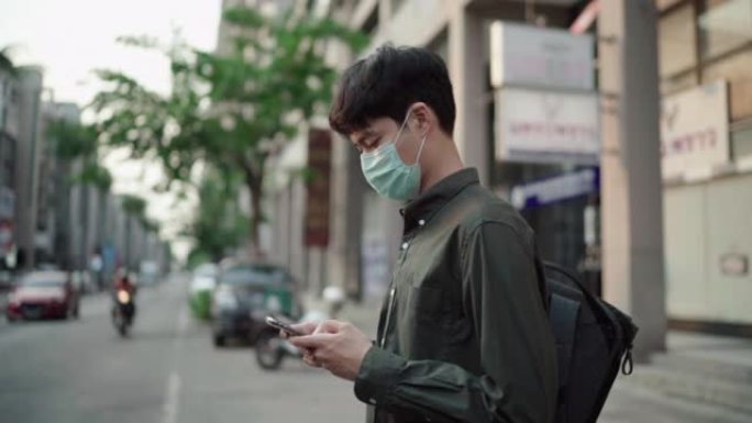 一名男子戴着口罩，在路上使用智能手机