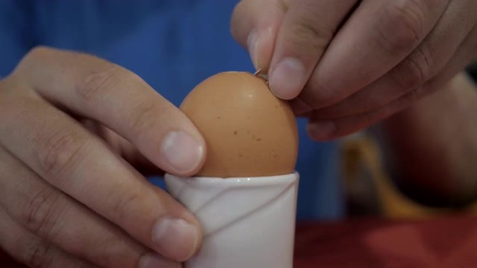 男性手在剥鸡蛋 ..慢动作。男人打扫干净，吃一个煮鸡蛋。特写。放在架子上煮鸡蛋。4K UHD