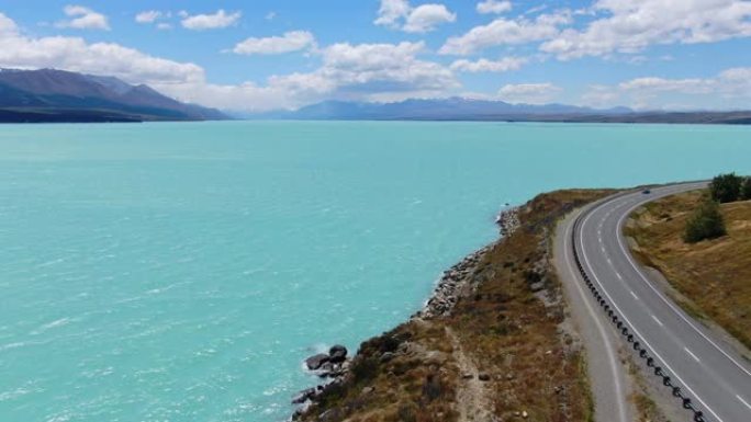 沿着新西兰南岛的高山湖泊普卡基湖沿岸的8号国道的令人惊叹的空中高角度无人机视图。水以其鲜明的鲜艳色彩