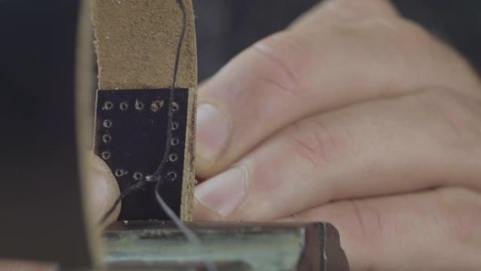 手工制作皮革表带的过程。工匠用针和线缝制皮革表带。手工皮革制品。电影院4k视频。C4k