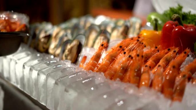 在海鲜餐厅，库克之手将新鲜的虾和牡蛎叠加在冰上。烹饪食谱。慢动作镜头。
