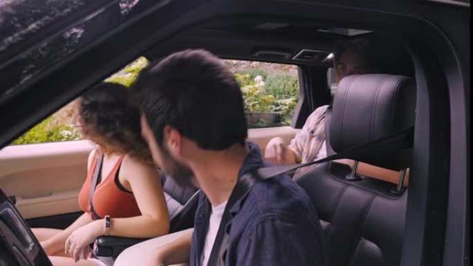 四名年轻人在SUV中听音乐并摇头