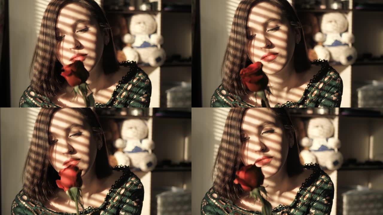 美丽的女孩坐在日落的窗边，看着红色的玫瑰花。情人节，2月14日，生日，周年纪念日，第一次约会概念。慢