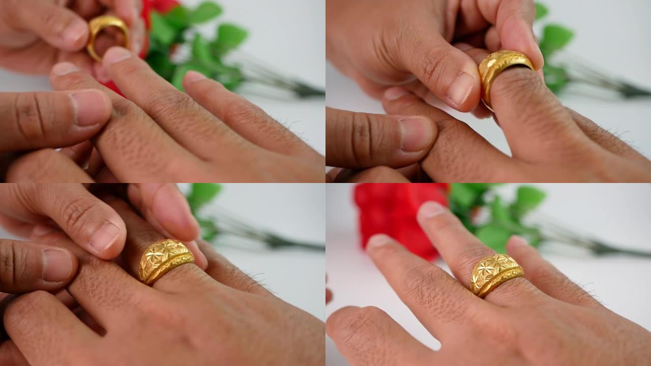 女人在情人节把金色订婚戒指放在男人的手上，订婚夫妇的手和红色玫瑰花束背景上的金戒指。