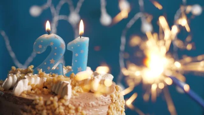 蓝色背景上有21号蜡烛和烟火的生日蛋糕。慢动作和特写视图