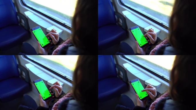 坐火车旅行时，女孩手持绿屏智能手机的俯视图。乘客女性在互联网上浏览，使用导航仪并坐在窗户附近。智能手