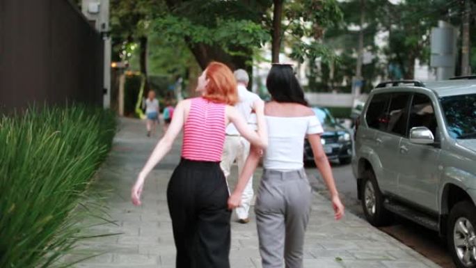 两个女朋友一起走在街上。向其他女性朋友倾斜的女孩应该