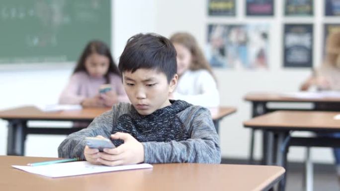 年轻的小学生在课堂上玩手机
