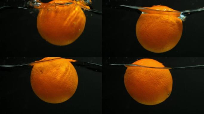 橙色水果以慢动作落在水中。在黑色背景上。