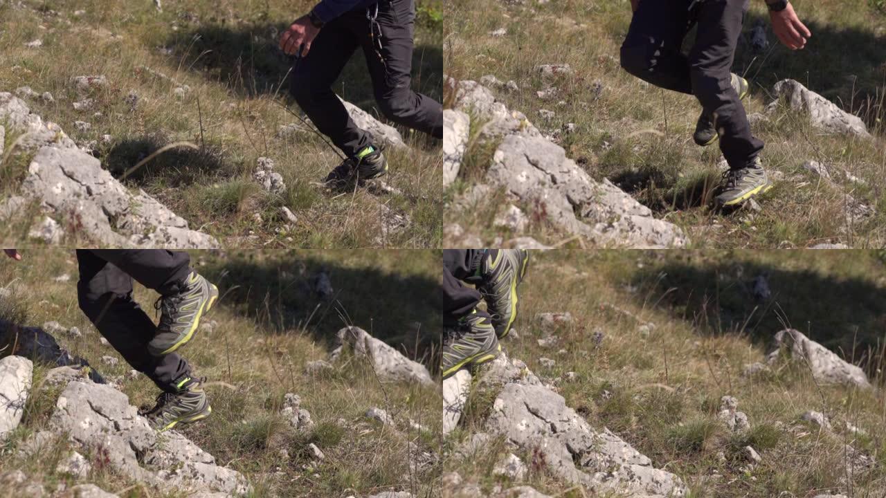 这个人跑过去跳过石头。草地和石头上的腿的特写