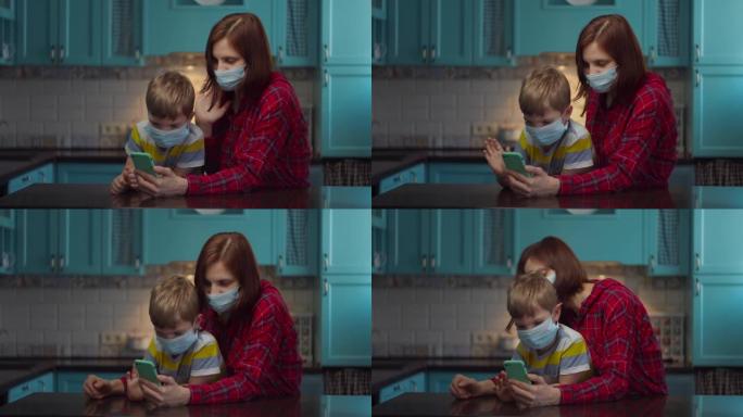30多岁的母亲和男孩戴着医用口罩与亲戚通过手机在线交谈，挥手致意。家庭在病毒的自我隔离。停止流行。