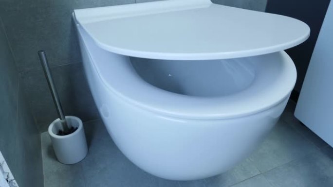 关闭马桶盖的特写视图。浴室白色厕所的特写视图。浴室的一部分，墙壁和地板上有白色厕所和灰色瓷砖