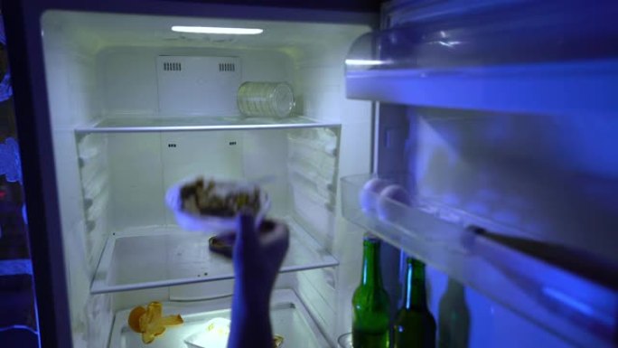 在冰箱里找食物的人。那家伙把剩下的食物放在冰箱里，然后拿了一瓶啤酒。