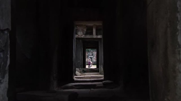 在吴哥窟寺庙废墟中行走的游客。树木生长在建筑物中。联合国教科文组织历史遗址。著名的旅游目的地为背包客