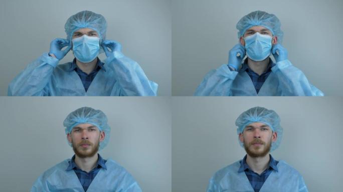 穿着防护医疗装备的男子在手术后脱下医用口罩。男性医生佩戴医用蓝色口罩，用于病毒感染的预防和保护。大流