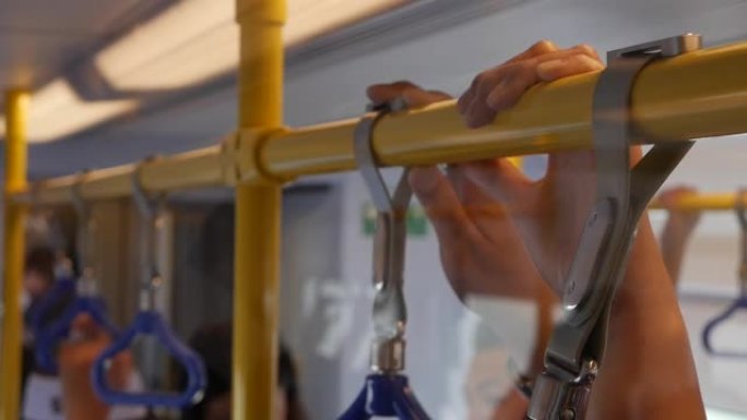 乘客在地铁或公共汽车上拿着扶手，在高峰时间上班。透过玻璃观看