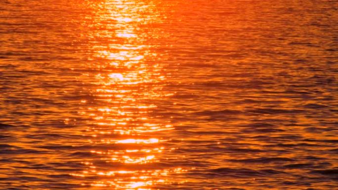 风景秀丽的海景，日落反射在海水中。带着笔记本走过的路人。热岩浆调色板。日落时不寻常的海景。海水反射日