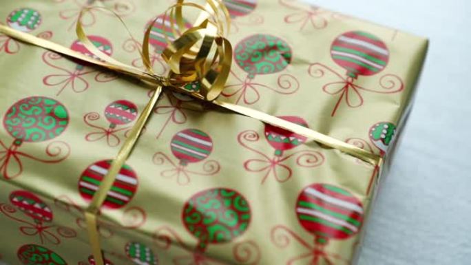 用金箔和纸包裹的圣诞礼物的特写视图，圣诞动机和白色背景上的丝带顶部，以120fps的慢动作捕捉。