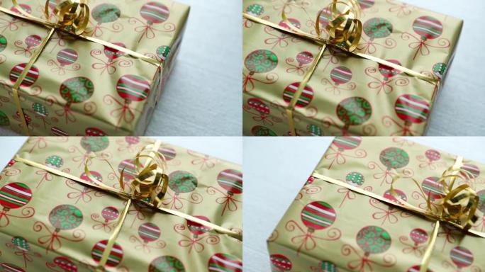 用金箔和纸包裹的圣诞礼物的特写视图，圣诞动机和白色背景上的丝带顶部，以120fps的慢动作捕捉。