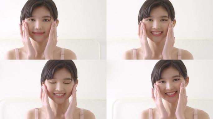 美丽的年轻亚洲女性化妆为面部柔软，女孩手触摸面部光滑涂抹面霜和乳液为年轻化，美丽完美与健康，皮肤护理