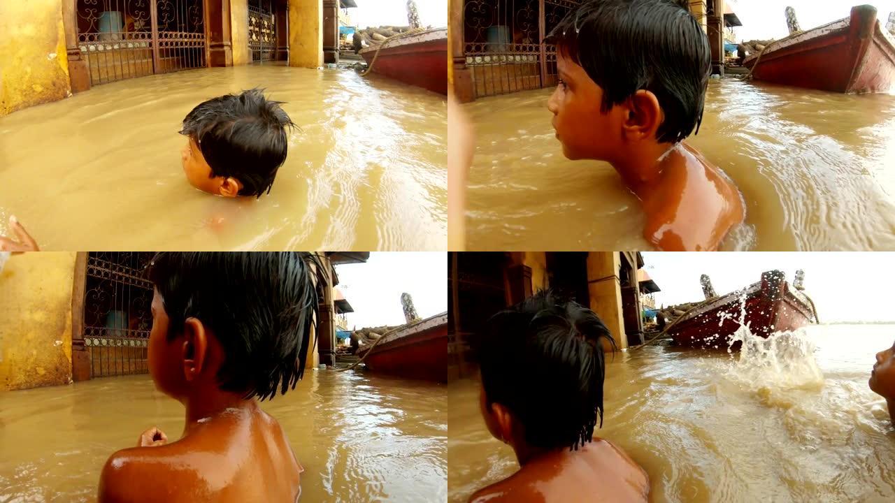 两个印度小男孩在陷入困境的水中沐浴，淹没了贝纳雷斯码头上的圣河恒河Manikarnika Ghat船