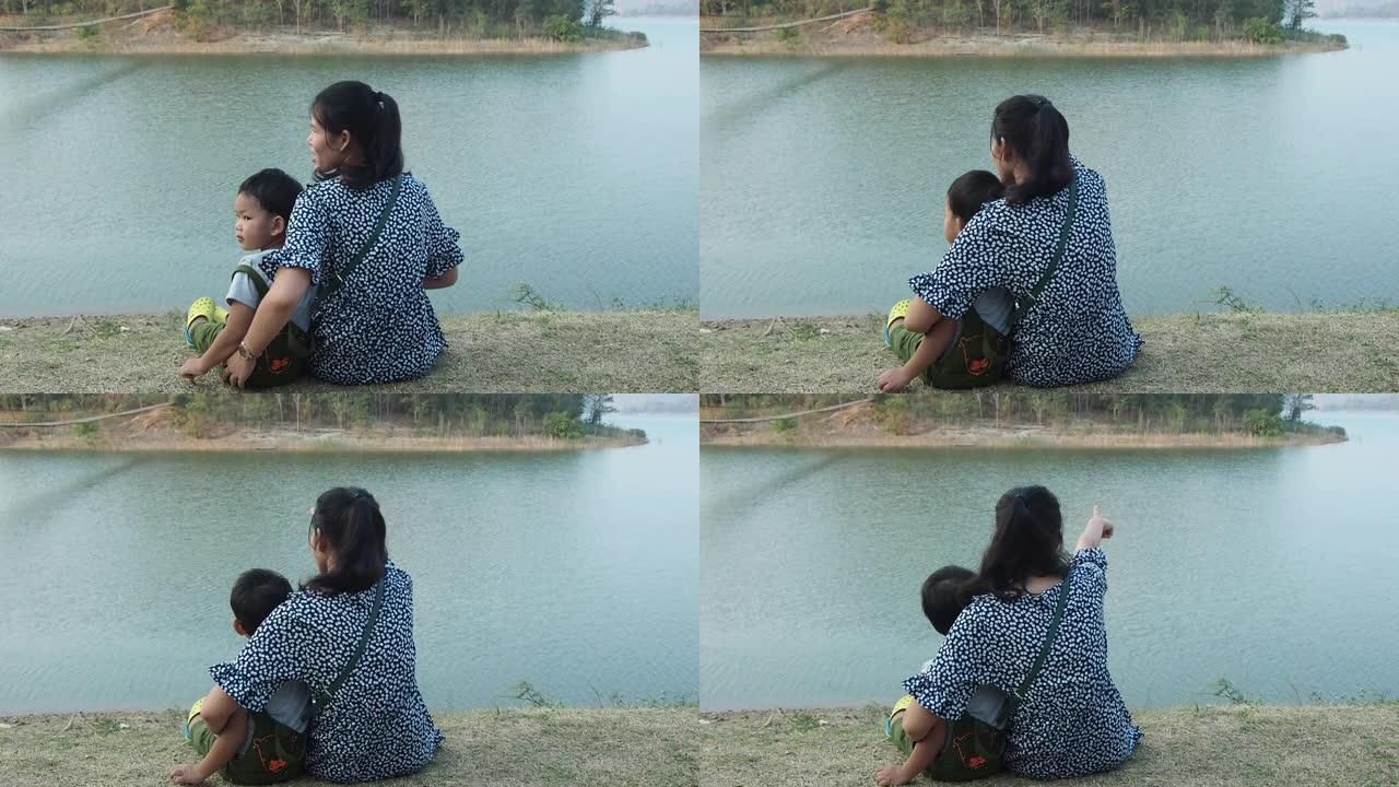 一位亚洲母亲带着孩子坐在河边