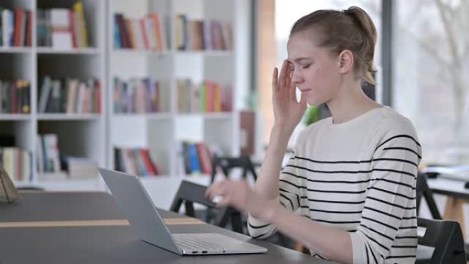 图书馆头痛的年轻女性使用笔记本电脑