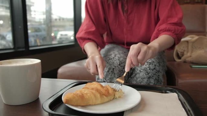 女人在咖啡馆吃早餐咖啡和羊角面包。