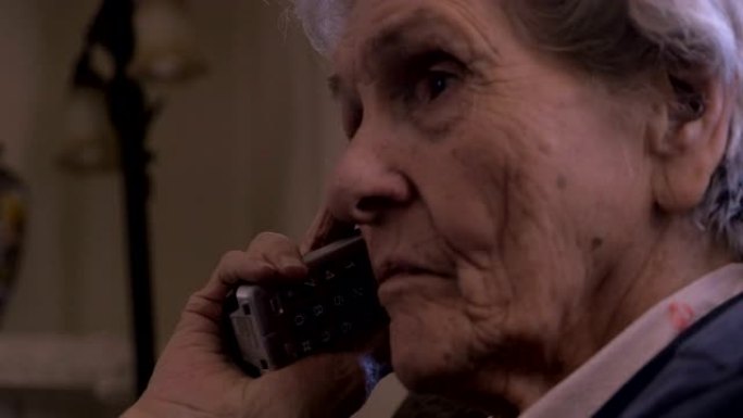 一名90岁的妇女在黑暗的房间里用无绳电话仔细聆听