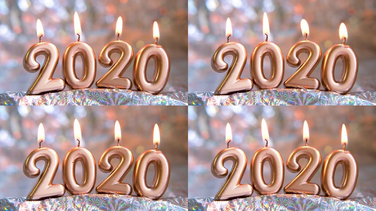 文本2020金色蜡烛燃烧。模糊的银色背景。圣诞快乐，新年快乐。选择性聚焦。创意现场贺卡。4k镜头