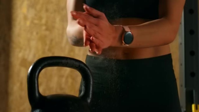 肌肉发达的女人在健身房用滑石粉拍手