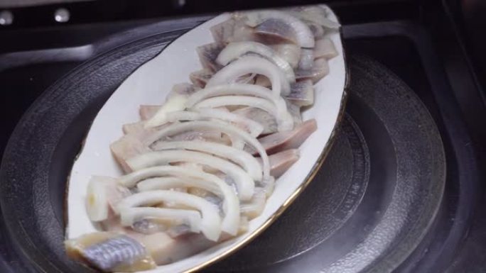 洋葱的鲱鱼片放在盘子里的油里。绕着圈旋转。