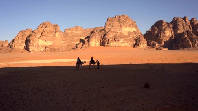 在阳光明媚的日子里，在约旦的瓦迪朗姆酒沙漠中行走的骆驼大篷车