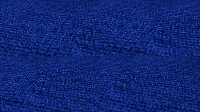 蓝色针织羊毛，套头衫面料是挥舞的背景。特写，纤维毛衣的宏观拍摄