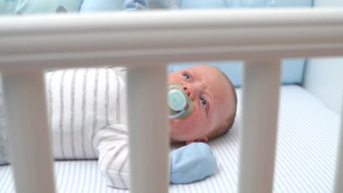 可爱的男婴躺在婴儿床里吮吸奶嘴中拍俯视图特写慢动作