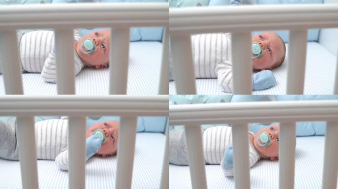 可爱的男婴躺在婴儿床里吮吸奶嘴中拍俯视图特写慢动作