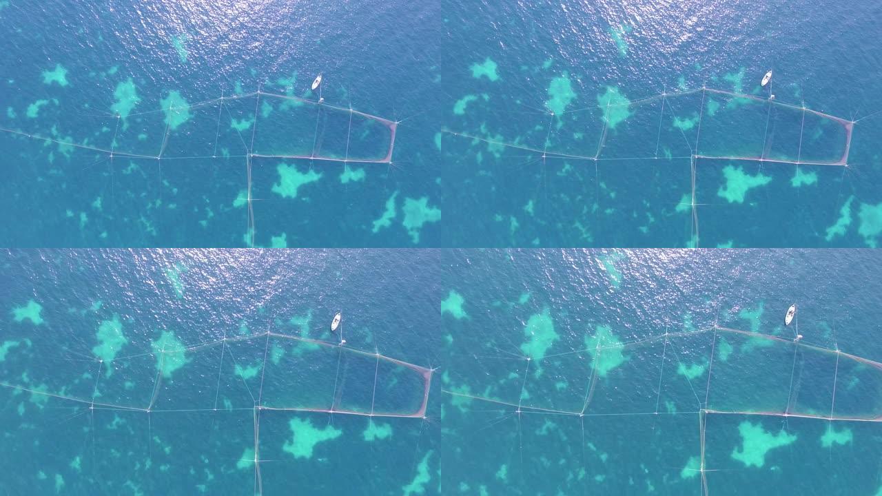 在蓝色的海和白色的小船中捕鱼的渔网。空中无人机镜头