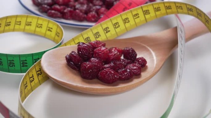 红色小红莓放在木勺和白色盘子里，浅灰色桌子上有明亮的颜色厘米