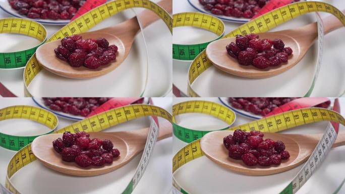 红色小红莓放在木勺和白色盘子里，浅灰色桌子上有明亮的颜色厘米