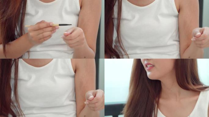 20-30岁的亚洲女性在涂抹前用油漆刷将唇膏的味道粘到她的手中。