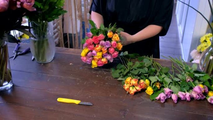 花店女人在商店里用五颜六色的小玫瑰做花束，双手特写。