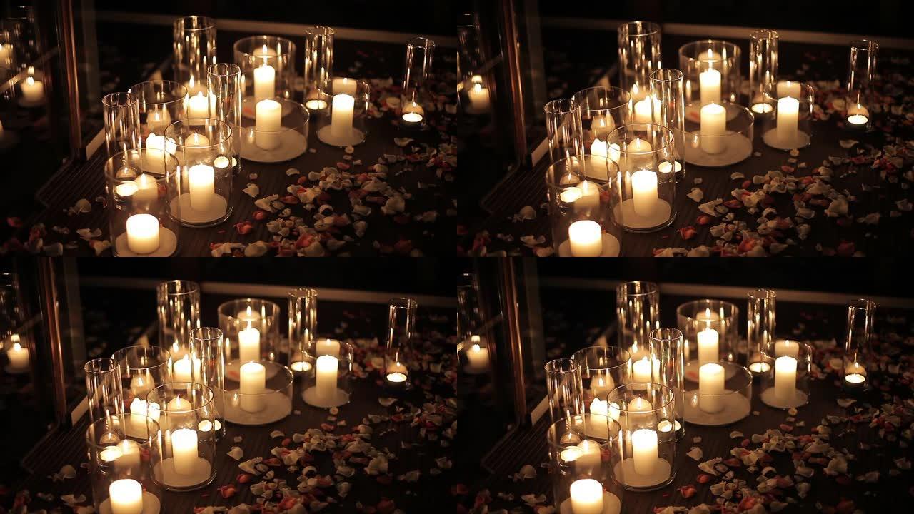 玻璃烧瓶中的蜡烛站在地板上，上面有玫瑰花瓣。