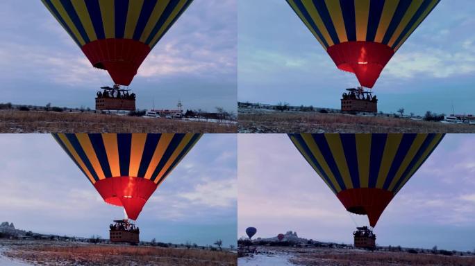 独自热气球在土耳其卡帕多细亚的白雪皑皑的风景下低飞