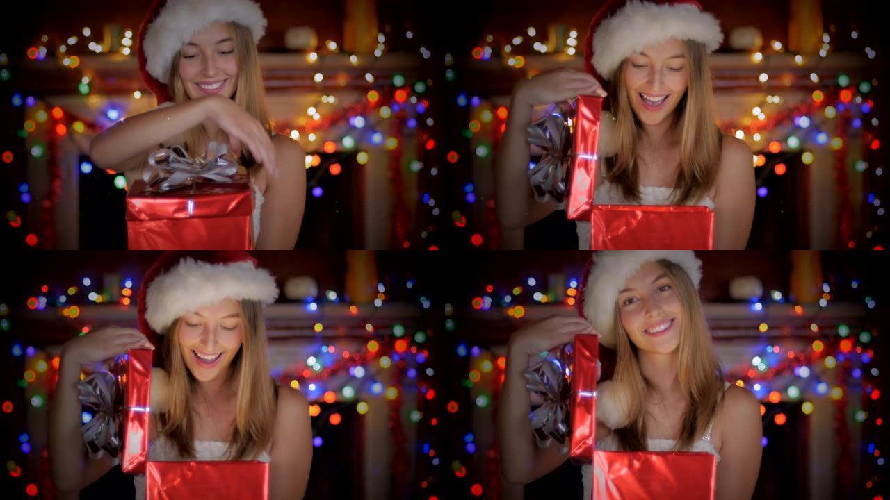 一位美丽的年轻女子戴着圣诞老人的帽子在晚上打开圣诞节礼物