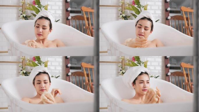 慢动作: 亚洲女性在浴缸里沐浴在她的身体和腿上。
