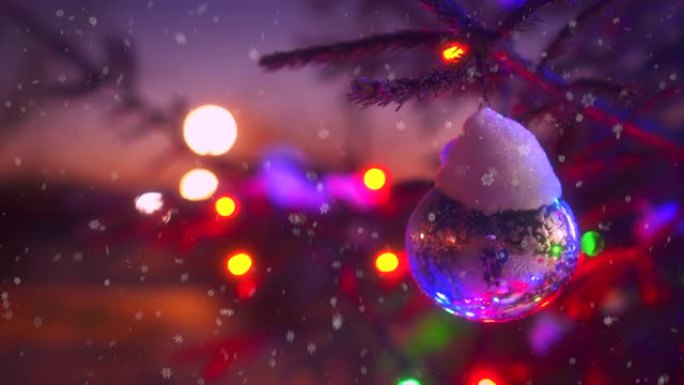 圣诞树的特写树枝，五颜六色的闪烁的灯光bokeh被飘落的雪包围
